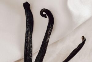 Elegant composition of dried vanilla beans on a delicate white fabric background.